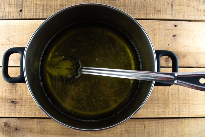 Dandelion syrup in a large pot on a wooden table.